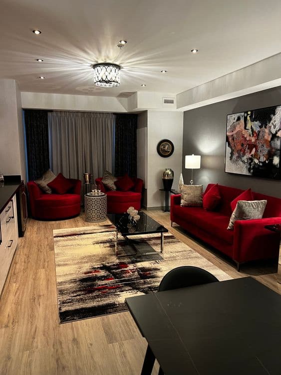 Modern living room with a red sofa, grey wall, and floral painting above.